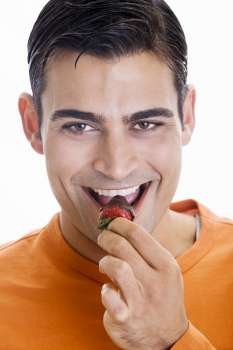 Portrait of a mid adult man eating a chocolate dipped strawberry
