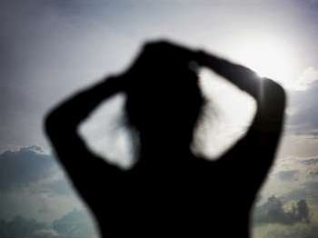 Silhouette of a young woman with her hands in her hair