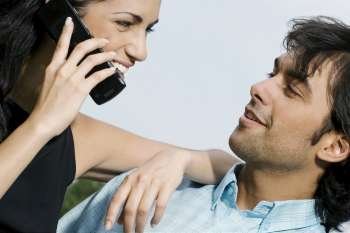 Close-up of a young woman talking on a mobile phone and looking at a young man