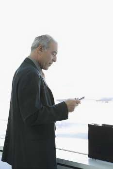 Side profile of a businessman operating a personal data assistant at an airport