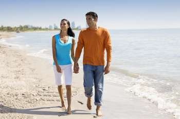 Young woman and a mid adult man walking on the beach