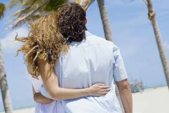 Mid adult couple walking on the beach with their arms around each other