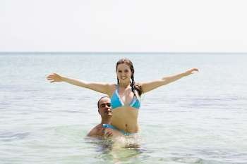 Mid adult man picking up a young woman in the sea