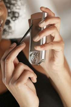 Close-up of a young woman holding a mobile phone and a stylus