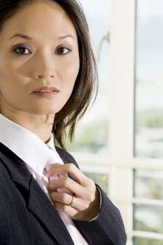 Side profile of a businesswoman adjusting her tie