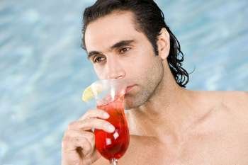 Close-up of a mid adult man drinking a cocktail near a swimming pool