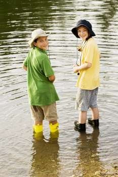 Rear view of two brothers fishing near a lake