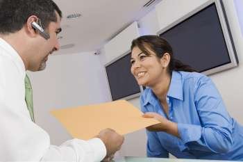 Receptionist giving a file to a businessman
