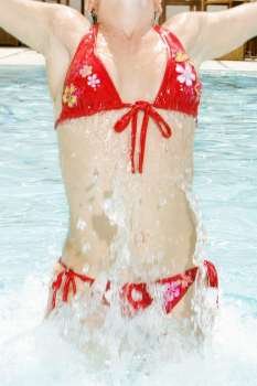 Young woman splashing water in a swimming pool