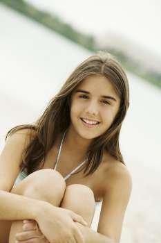Portrait of a teenage girl sitting on the beach smiling