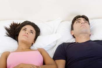 High angle view of a young couple lying on the bed and looking up