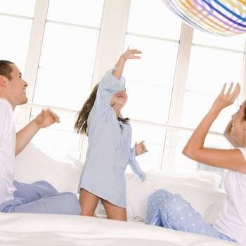 Parents playing with their daughter on the bed