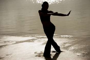 Silhouette of a mid adult woman exercising on the beach
