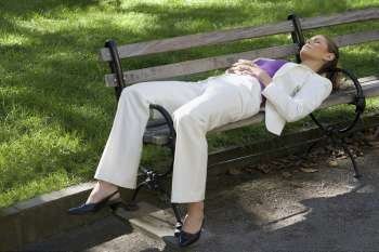 Businesswoman sleeping on a bench in a park