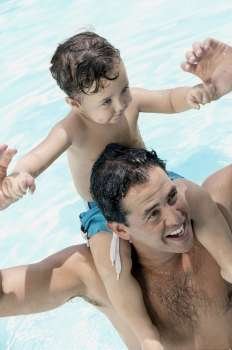 High angle view of a father carrying his son on his shoulders at a swimming pool