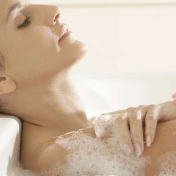 Close-up of a young woman lying in a bathtub with her eyes closed