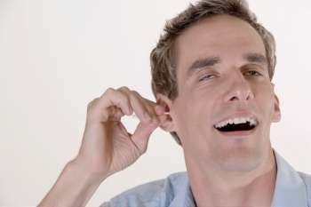 Close-up of a mid adult man cleaning his ear with a cotton swab