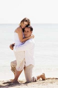 Portrait of a young woman and a mid adult man embracing each other on the beach