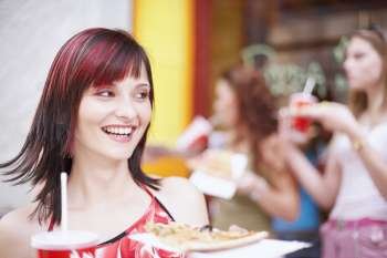 Young woman holding a plate with a cold drink and a slice of pizza 