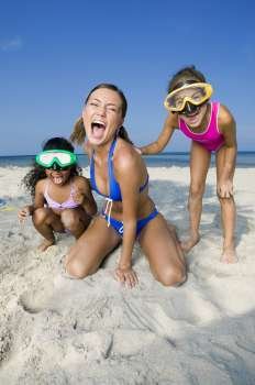 Close-up of a young woman and two girls on the beach