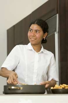 Maid preparing food in the kitchen and smiling