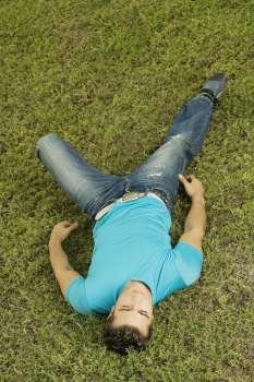 High angle view of a mid adult man lying on the grass