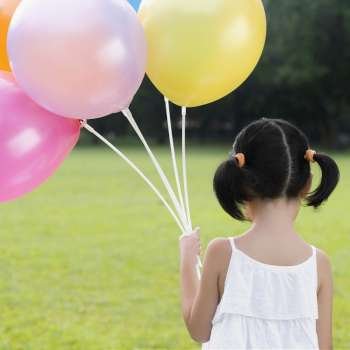 Rear view of a girl holding balloons in a park