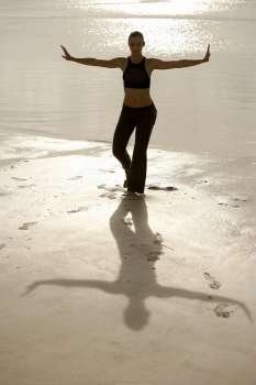 High angle view of a mid adult woman standing in the tree pose on the beach
