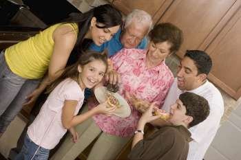Three generation family eating food from a plate and smiling