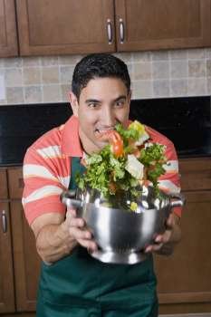 Mid adult man mixing salad in a colander
