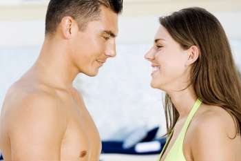 Side profile of a young couple looking at each other at the poolside
