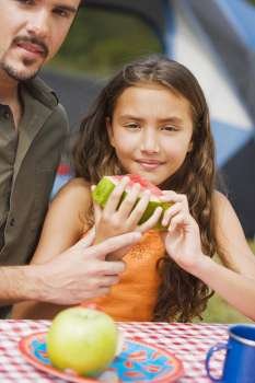 Close-up of a father and his daughter holding a slice of watermelon