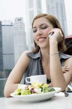 Young woman talking on a mobile phone at a sidewalk cafe