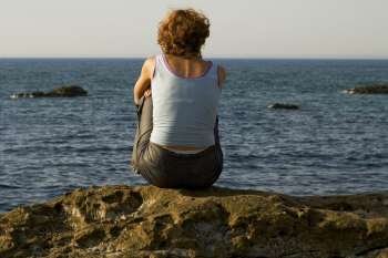 Rear view of a woman sitting on a rock, Baie De Biarritz, Biarritz, Pyrenees-Atlantiques, France