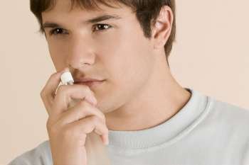 Close-up of a young man smelling a perfume