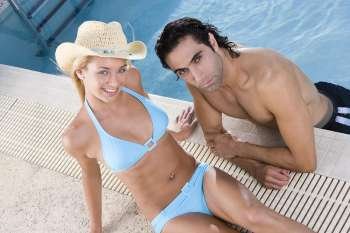 High angle view of a young woman and a mid adult man at the poolside