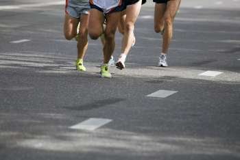 Low section view of male athletes running on a road