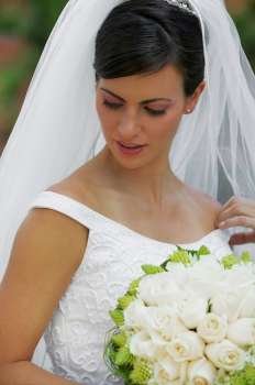 Close-up of a bride holding a bouquet of flowers and looking down