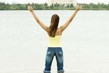 Rear view of a girl standing in water with her arms outstretched