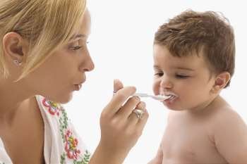 Close-up of a mid adult woman feeding her son with a spoon
