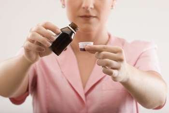 Female nurse pouring syrup into a bottle cap