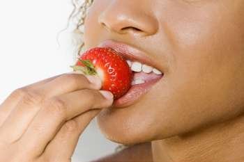 Close-up of a young woman eating a strawberry
