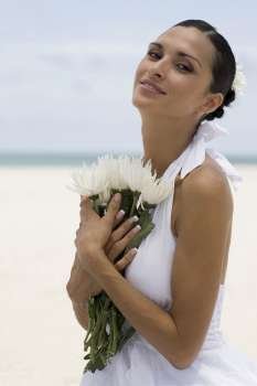Portrait of a young woman holding flowers on the beach