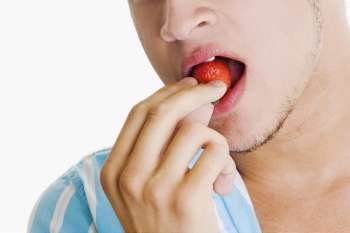 Close-up of a young man eating a strawberry