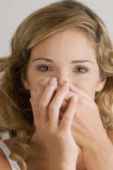 Portrait of a young woman covering her mouth with her hands