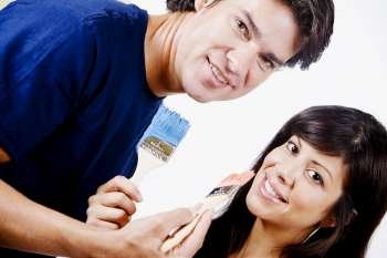 Portrait of a couple holding paintbrushes and smiling