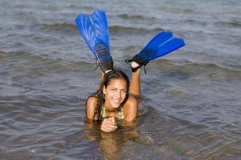 Portrait of a teenage girl lying in water and wearing flippers