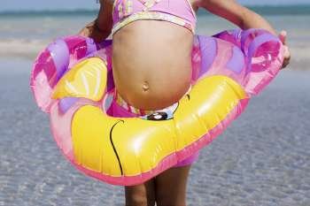 Mid section view of a girl in an inflatable ring standing on the beach