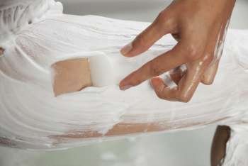 Low section view of a woman applying shaving cream on her leg