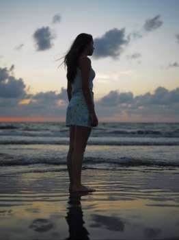 Side profile of a teenage girl standing on the beach